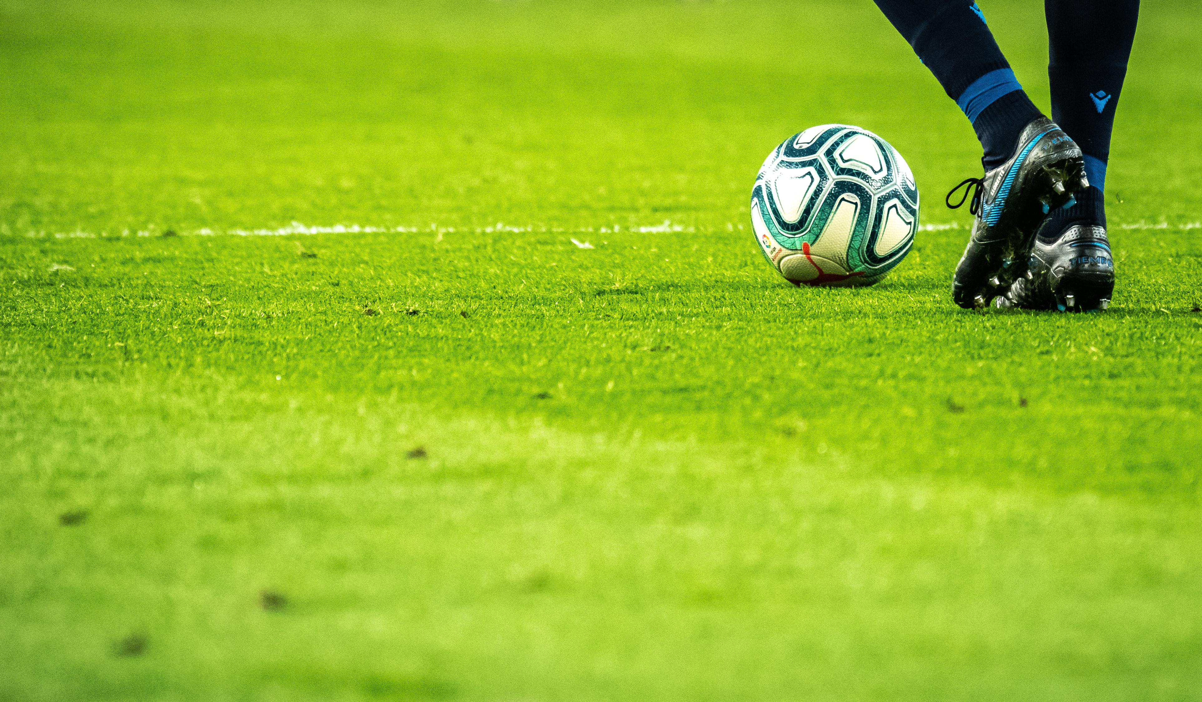 feet of soccer player standing beside a ball