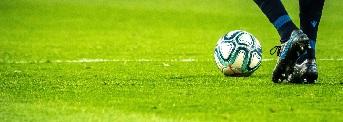 feet of soccer player standing beside a ball